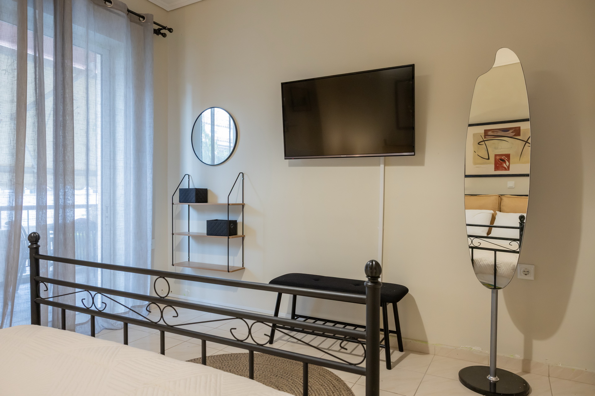 The bedroom with smart TV, full-length mirror and balcony door