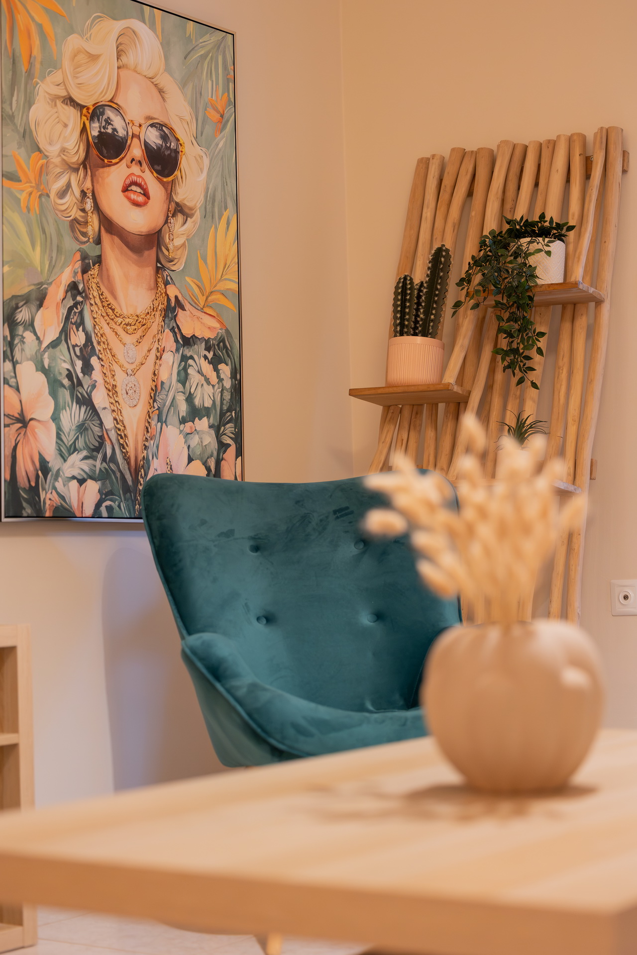 Teal velvet armchair beside modern artwork and a wooden shelf