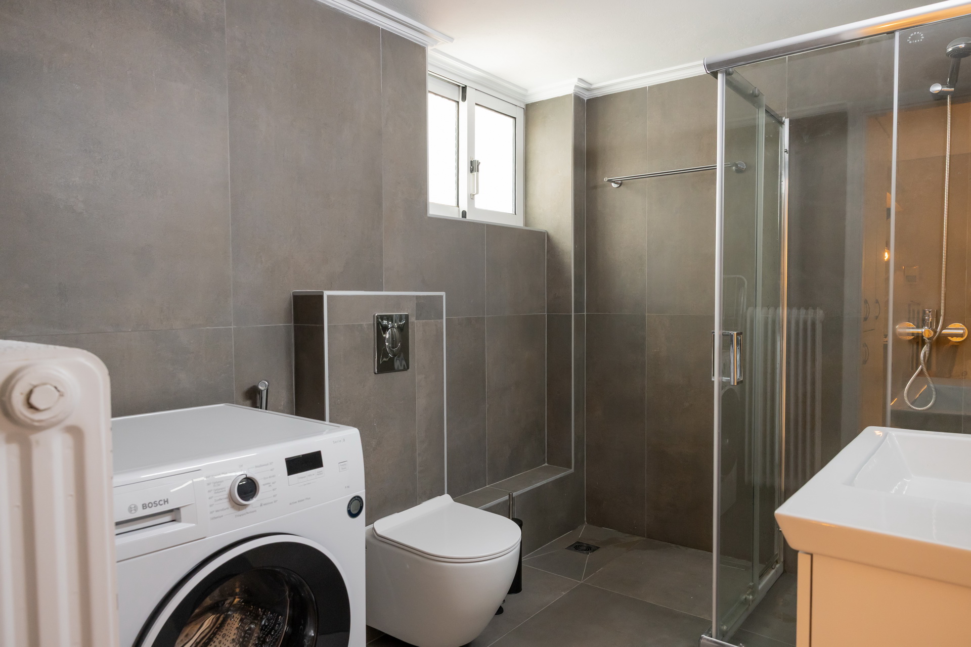 The bathroom with glass shower cabin and washing machine
